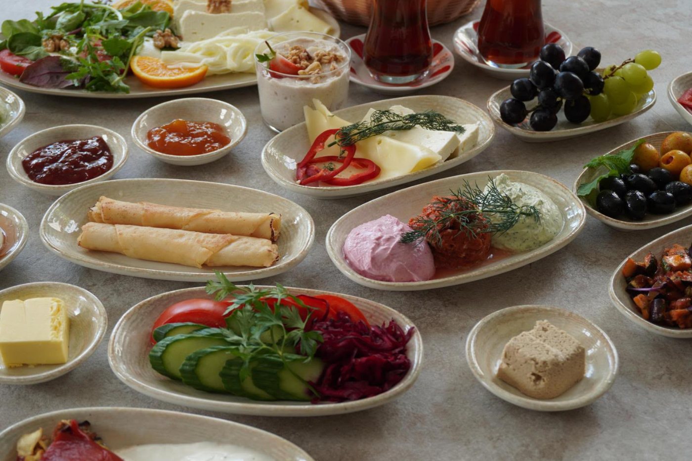 Gedeckte Frühstückstafel mit Pfannengerichten, Käse, Aufstrichen und Teegläsern